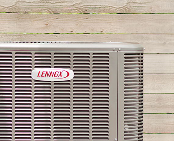 Close-up view of a Lennox brand outdoor air conditioning unit with a wooden fence in the background. Close-up view of a Lennox brand outdoor air conditioning unit with a wooden fence in the background.