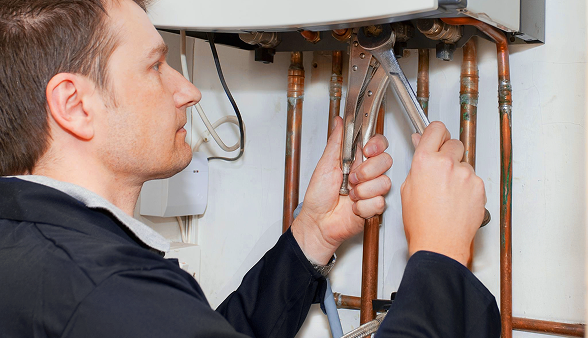 A Bosanac company technician adjusts copper pipes under a boiler using two wrenches, ensuring proper maintenance and function. A Bosanac company technician adjusts copper pipes under a boiler using two wrenches, ensuring proper maintenance and function.